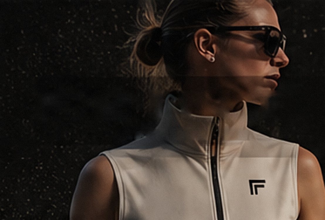A woman in sunglasses wearing a bone FEINT zip vest